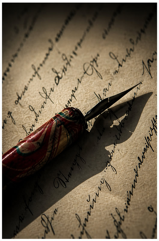 antique pen resting on parchment with writing